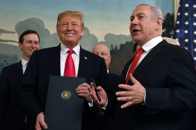 President Donald Trump smiles as he holds a proclamation as Israeli Prime Minister Benjamin Netanyahu, right, speaks in the Diplomatic Reception Room at the White House in Washington, Monday, March 25, 2019. Trump signed an official proclamation formally recognizing Israel's sovereignty over the Golan Heights. (AP Photo/Susan Walsh)