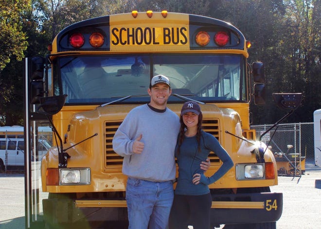 In this photo taken with a timer Oct. 30, 2018, Jack Labosky, left, and Madi Hiatt pose after purchasing a school bus in Lynchburg, Va. Labosky is a minor league pitcher in the Tampa Bay Rays organization, and he and Hiatt, his girlfriend, plan to live out of the bus during his first full professional season. [Madi Hiatt via AP]