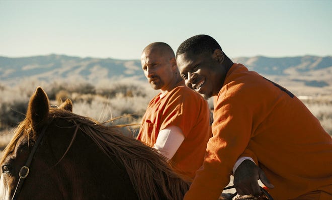 Matthias Schoenaerts, left, and Jason Mitchell play prison inmates in a rehabilitation program that uses wild horses in "The Mustang." [Focus Features]
