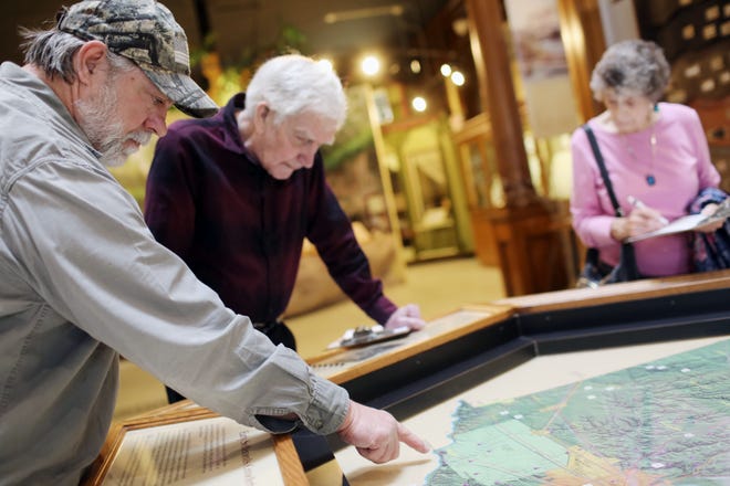 David Hall, left, points to a topographical history of Des Moines County display while taking part in an "Arti-FACT Search" along with Bill Bloomberg and Hall's aunt Martha Rante, during a 10th anniversary celebration open house Thursday for the Des Moines County Historical Society at 501 N. Fourth St. in Burlington. The historical society opened in 2009 in the then-110-year-old former Burlington Public Library building. [John Lovretta/thehawkeye.com]