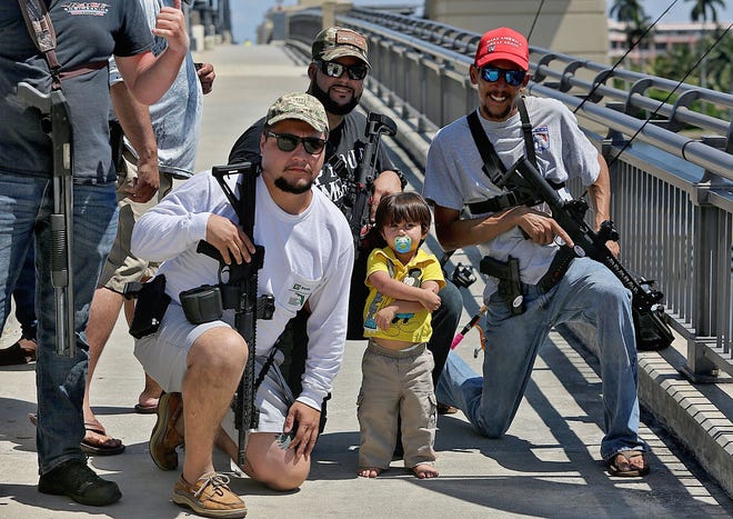 Lukas Garcia, left, Ruben Espinosa, Slade Espinosa, 2, and Michael Taylor, members of Florida Carry, a non-profit organization that promotes gun rights in Florida, hold an assembly on the Royal Park Bridge on Saturday. [Tim Stepien/palmbeachdailynews.com]