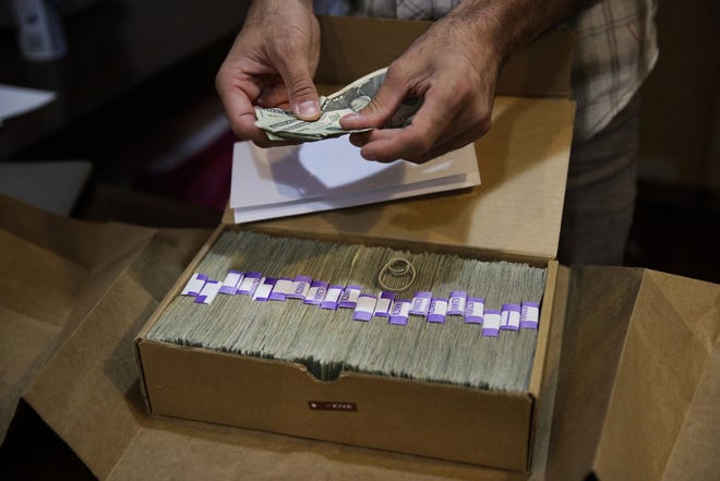 The owner of a medical marijuana dispensary prepares his monthly tax payment, over $40,000 in cash, at his Los Angeles store. Legislation that would provide federal protection for financial institutions that serve state-authorized marijuana and related businesses has passed a U.S. House committee. [AP file / Jae C. Hong]