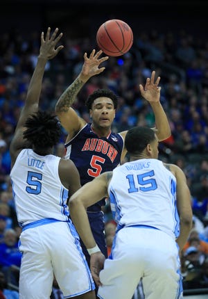 Auburn's Chuma Okeke (5) passes over North Carolina's Nassir Little (5) and Garrison Brooks on Friday. Fifth-seeded Auburn upset top seed North Carolina 97-80 in a Midwest Region semifinal in Kansas City, Mo. [Orlin Wagner/The Associated Press]