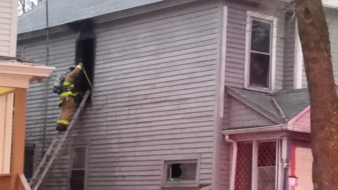 A Topeka firefighter used a ladder to enter a second-story window at a house where firefighters put out a blaze Friday morning. [Tim Hrenchir/The Capital-Journal]