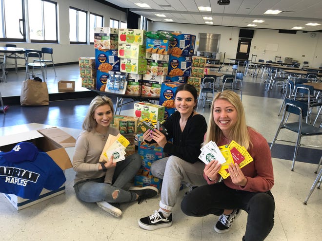 Anna Schafer, Elizabeth Halfmann and Caroline Lewis, senior members of the Adrian chapter of the Subdeb Club, pose Thursday with items they packed for students in the Adrian High School “Families in Transition” program.