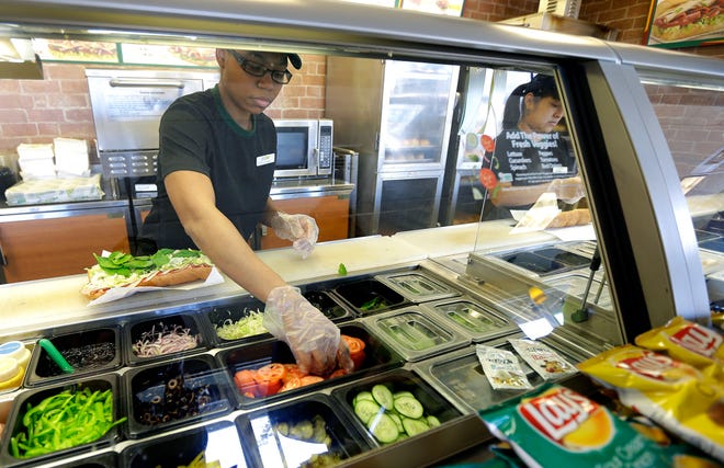 Workers make sandwiches at a Subway franchise in Seattle in 2015. As sales continue to slump, the chain closed more than 1,100 U.S. locations in 2018, up from 800 the year before. [AP, file / Ted S. Warren]