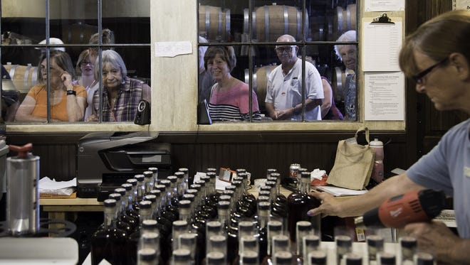 Visitors to the St. Augustine Distillery in St. Augustine watch as caps are put on bottles of the distillery's bourbon in 2016. The business is celebrating its fifth anniversary this week. [PETER WILLOTT/THE RECORD]