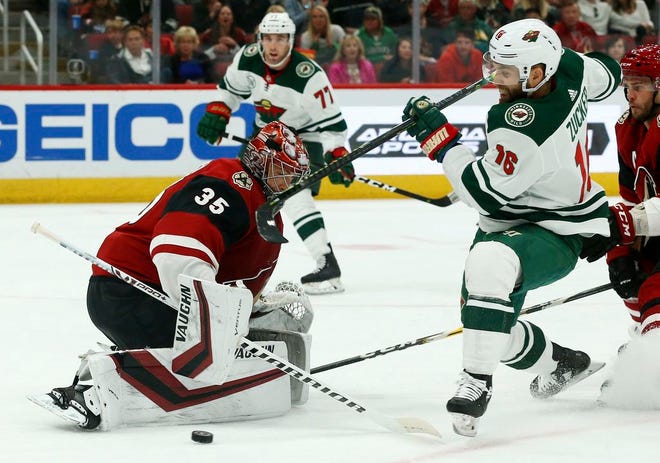 Arizona Coyotes goaltender Darcy Kuemper (35) makes a save on a shot by Minnesota Wild left wing Jason Zucker (16) as Coyotes defenseman Niklas Hjalmarsson, right, defends and Wild defenseman Brad Hunt (77) looks on during the first period Sunday in Glendale, Ariz.