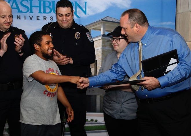 Washburn University employee Gary “Junior” Darby Bey is recognized on Friday by university police chief Chris Enos for turning in a large amount of money he found to the department. Bey's supervisor, Rebecca Manis, who also was honored, looks on behind Enos. [Washburn University]