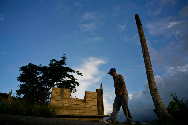 FILE - In this Sept. 8, 2018, file photo, Ramon Alicea Burgos walks past his palm tree, with its top broken off one year ago by Hurricane Maria one outside his partially rebuilt home in the mountain town of Barranquitas, Puerto Rico. A fight between President Donald Trump and Democrats over hurricane relief for Puerto Rico is imperiling a widely backed disaster aid bill that is a top priority for some of Trump’s southern GOP allies. (AP Photo/Ramon Espinosa, File)