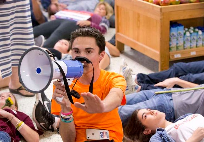 Marjory Stoneman Douglas High School student David Hogg speaks as demonstrators lie on the floor at a Publix Supermarket in Coral Springs, Fla., Friday, May 25, 2018. Students from the Florida high school where 17 people were shot and killed earlier this year did a "die in" protest at a supermarket chain that backs a gubernatorial candidate allied with the National Rifle Association. Shortly before the the "die-in" Publix announced that it will suspend political donations. (AP Photo/Wilfredo Lee)