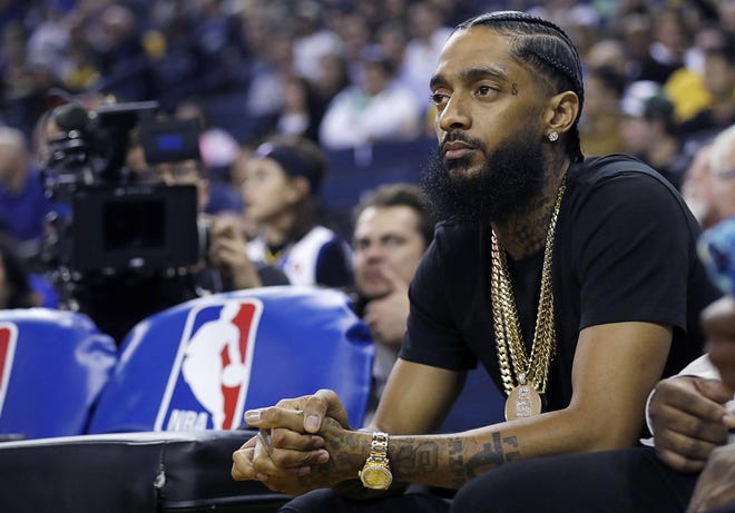 In this March 29, 2018, file photo, rapper Nipsey Hussle watches an NBA basketball game in Oakland, Calif. The Grammy-nominated and widely respected West Coast rapper has been shot and killed outside his Los Angeles clothing store, Los Angeles Mayor Eric Garcetti said Sunday. He was 33. [AP Photo/Marcio Jose Sanchez, File]