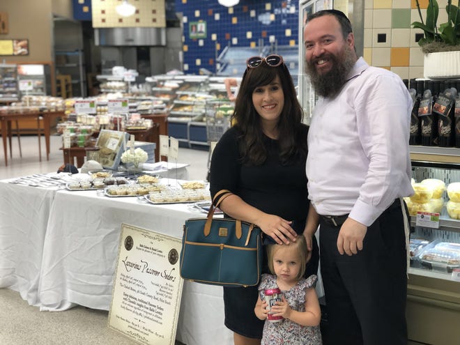 Rebbetzin Hindel Levitin and Rabbi Zalman Levitin stand with their daughter, Shula Levitin, in front of The Chabad House's display at "Matzah in the Aisles of Publix" on March 28. The next event is at 1 p.m. Thursday. [Courtesy Chabad House]