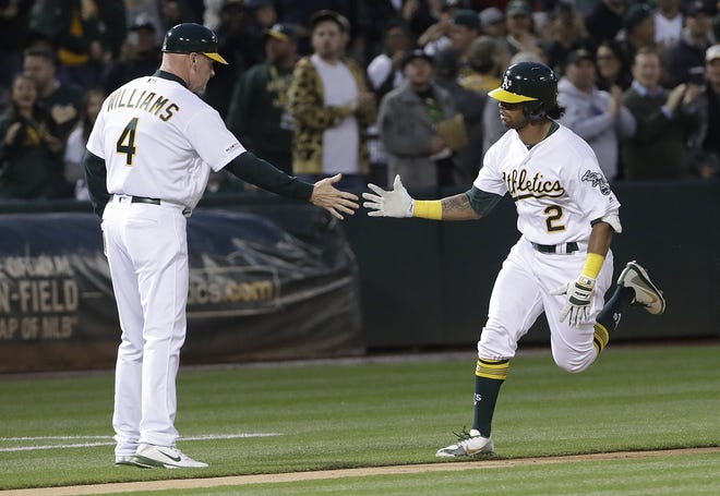 The Oakland Athletics' Khris Davis, right, is congratulated by third base coach Matt Williams after hitting a solo home run against the Boston Red Sox during the second inning Monday in Oakland. The A's won 7-0. [JEFF CHIU/THE ASSOCIATED PRESS]