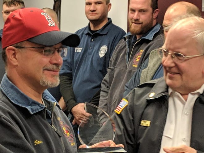 Steven Couture receives a plaque for his 20 years of service as part of the Millbury Fire Department. He is pictured here with Chief Richard Hamilton. [Steve Balestrieri photo | Millbury-Sutton Chronicle]