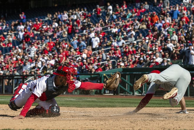 Washington Nationals catcher Kurt Suzuki, left, misses the tag on Philadelphia Phillies' Scott Kingery at home plate during the eighth inning of a MLBl game at Nationals Park Wednesday. The Phillies took the lead on the play, but gave up the lead in the bottom of the inning. [AP PHOTO/ALEX BRANDON]