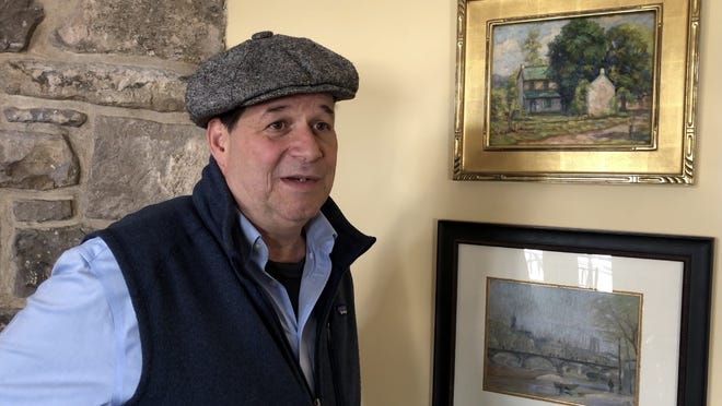 Paul Gratz, owner of the Gratz Gallery and Conservation Studio in Plumstead, hangs artworks in the Centre Bridge Inn. [JAMES MCGINNIS / STAFF]