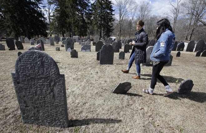 Christy Pottroff, assistant professor of English at Merrimack College, left, and Merrimack College junior Taylor Galusha, of Wethersfield, Conn., walk through an old burial ground, in North Andover, Mass., on March 19, 2019. A memorial marker for poet Anne Bradstreet, not shown, is at the cemetery. (AP Photos/Steven Senne)