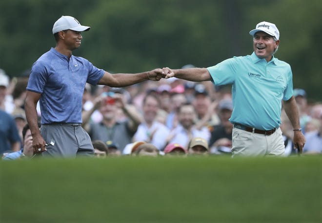 Tiger Woods and Fred Couples exchange a fist bump after they both hit their tee shots close to the cup on the par-3 No. 12 hole during a practice round for the Masters golf tournament on Monday. (Curtis Compton/Atlanta Journal-Constitution via AP)