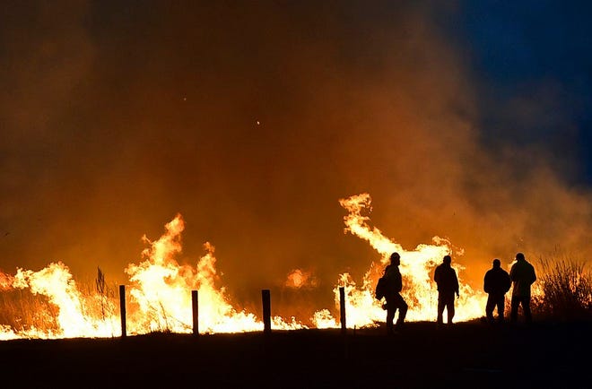 Lame Deer, Mont., residents watch Sunday as a fire races across a field on the edge of town.
