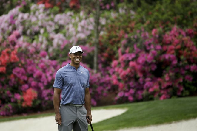 Tiger Woods smiles as he walks off the 13th green during a practice round Monday for the Masters at Augusta National Golf Club in Augusta. [CHARLIE RIEDEL/THE ASSOCIATED PRESS]