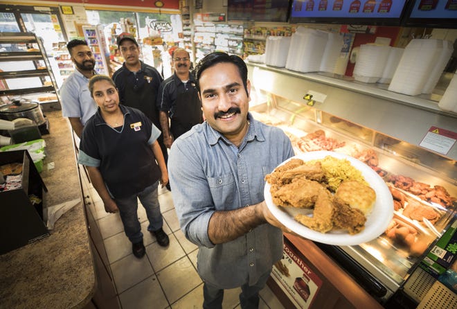 Anthony Mankidiyan holds a plate of his Indian spiced fried chicken he and his employees make at the Chevron station store in Lakeland. [ERNST PETERS/THE LEDGER]