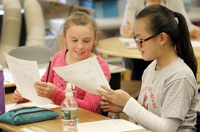 Students Katherine McGuttrick, 11, and Kelly Lee, 10, read letters from Spanish students on Wednesday, April 10, 2019. Greg Derr/The Patriot Ledger