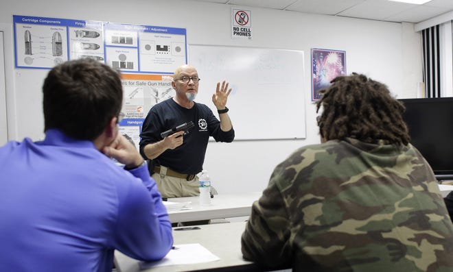 In this Jan. 5, 2016 photo, Mike Weinstein, director of training and security at the National Armory gun store and gun range, shows how to safely fire a Glock 9mm handgun during a concealed weapons permit class in Pompano Beach. [AP Photo/Lynne Sladky, File]