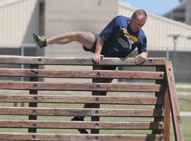 Lake County Sheriff Peyton Grinnell jumps a wall during a fitness test on Friday in Tavares. Grinnell and his leadership team ran an obstacle course as part of the department's fitness requirement. [Tom Benitez/Correspondent]