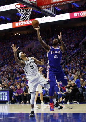 Philadelphia's Joel Embiid puts up the shot as he is fouled by Brooklyn's Jarrett Allen, left, during the first half in Game 1 of a first-round NBA basketball playoff series on Saturday in Philadelphia. [CHRIS SZAGOLA/THE ASSOCIATED PRESS]