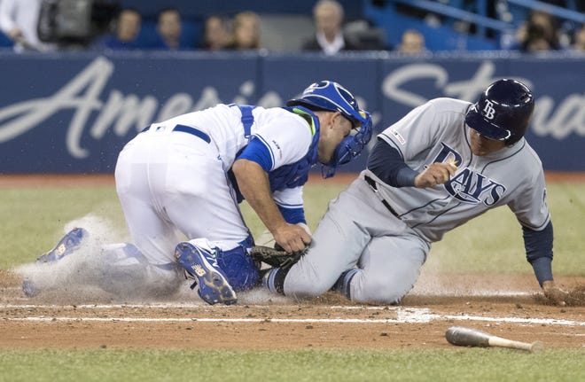 Toronto Blue Jays catcher Luke Maile hangs on to the ball after tagging out Tampa Bay's Avisail Garcia at home plate in the seventh inning on Saturday in Toronto. [FRED THORNHILL/THE ASSOCIATED PRESS]
