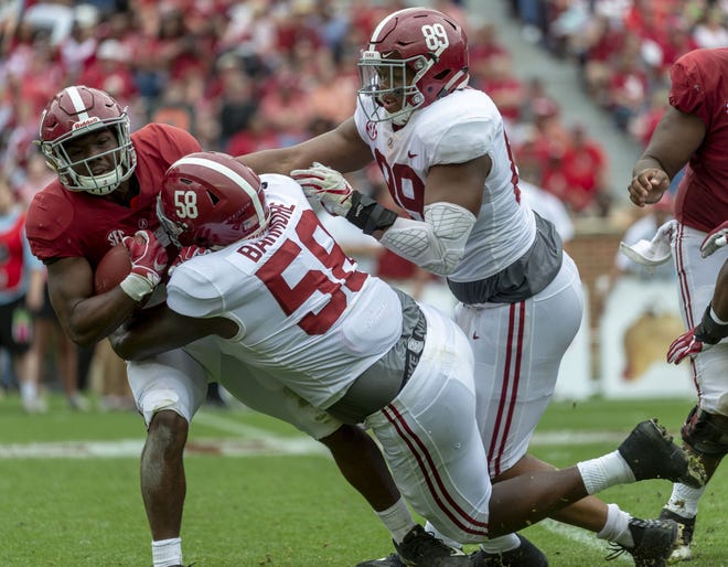 Alabama's Christian Barmore tackles teammate Jerome Ford while the Tide's LaBryan Ray assists during Saturday's A-Day game. [Vasha Hunt/The Associated Press]