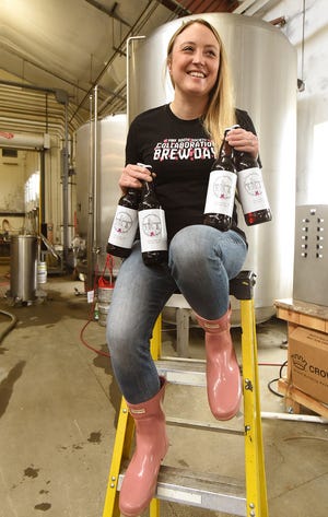 Pink Boots Society member Amy Desrosiers proudly shows some just bottled Burly Girly Barleywine at Buzzards Bay Brewing in Westport April 12. [Herald News Photo | Jack Foley]