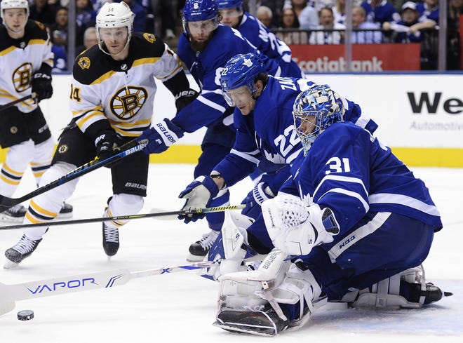 Toronto Maple Leafs goaltender Frederik Andersen (31) pokes the puck away as Boston Bruins right wing Chris Wagner (14) and Maple Leafs defenseman Nikita Zaitsev (22) look on during third-period playoff action in Toronto on Monday. [NATHAN DENETTE/THE CANADIAN PRESS]