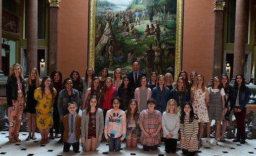 State Representative Tim Butler, back center, is surrounded by members of the Lady Wolverines of West Lincoln - Broadwell basketball and volleyball teams as they were honored at the Capitol in Springfield. [Photo submitted]