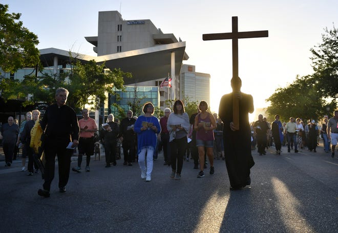 The Rev. Christian Wood carries a wooden cross during the Stations of the Cross procession in this March 31, 2018, file photo. Pastors, priests and preachers from more than 30 Sarasota area congregations will lead the pilgrimage that gathers at 7:15 a.m. in front of the Regal Hollywood 11 theaters on Friday. [Herald-Tribune staff photo / Mike Lang]