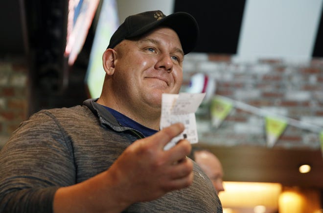 James Adducci holds up his winning ticket Monday in Las Vegas after winning more than $1 million betting on Tiger Woods to win the Masters. [JOHN LOCHER/THE ASSOCIATED PRESS]
