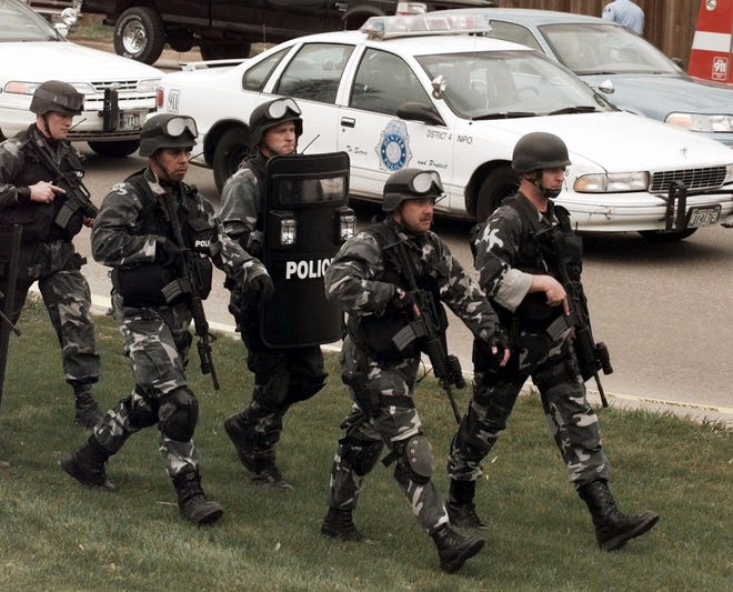 FILE - In this April 20, 1999, file photo, members of a police SWAT team march to Columbine High School in Littleton, Colo., as they prepare to do a final search of the school after two gunmen opened fire on campus. The shooting shocked the country as it played out on TV news shows from coast to coast. [Ed Andrieski/AP Photo]