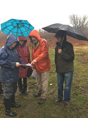 Susan Anderson, left, chairwoman of the Tiverton Historic Preservation Advisory Board, Tiverton Planning Board Chairwoman Susan Gill, forester Marc Tremblay and Planning Board member Paul Amaral review a site plan of the solar project in one of the farm fields Saturday morning. [MARCIA POBZEZNIK/DAILY NEWS PHOTO]
