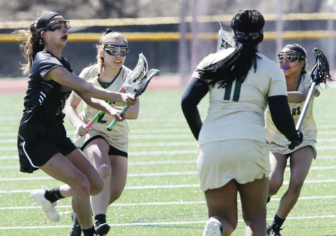Old Colony's Raquel Rodrigues, far left, fires her 100th career goal by GNB Voc-Tech defenders. [MIKE VALERI/THE STANDARD-TIMES/SCMG]