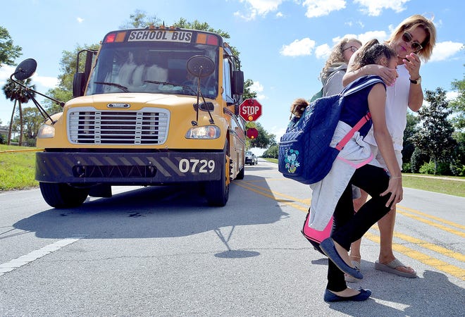 Liliana Rozo greets daughter Juliana Cruz as she crosses the street at a bus stop on Grand Island Shores Rd. on Tuesday, April 11, 2017 in Eustis, Fla. She and other parents do this to make sure that the children are able to cross the road safely. [DAILY COMMERCIAL FILE]
