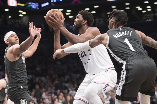 Philadelphia 76ers center Joel Embiid goes to the basket against Brooklyn Nets guard D'Angelo Russell (1) and forward Jared Dudley during the first half of of Game 4 of a first-round NBA playoff series on Saturday in New York. [MARY ALTAFFER/THE ASSOCIATED PRESS]