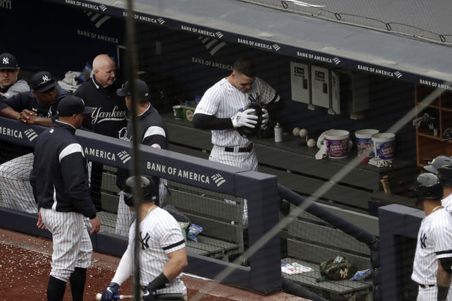 Aaron Judge clenches his helmet in the dugout after straining the oblique muscle on the left side of his abdomen while hitting a sixth-inning single against Kansas City on Saturday. [Julio Cortez/Associated Press]