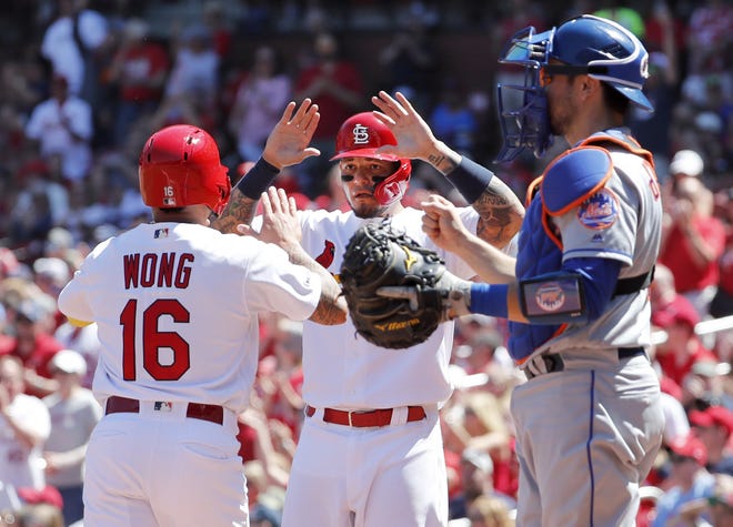 The St. Louis Cardinals' Kolten Wong, left, and teammate Yadier Molina celebrate after scoring past New York Mets catcher Travis d'Arnaud during the second inning Sunday in St. Louis. [JEFF ROBERSON/THE ASSOCIATED PRESS]