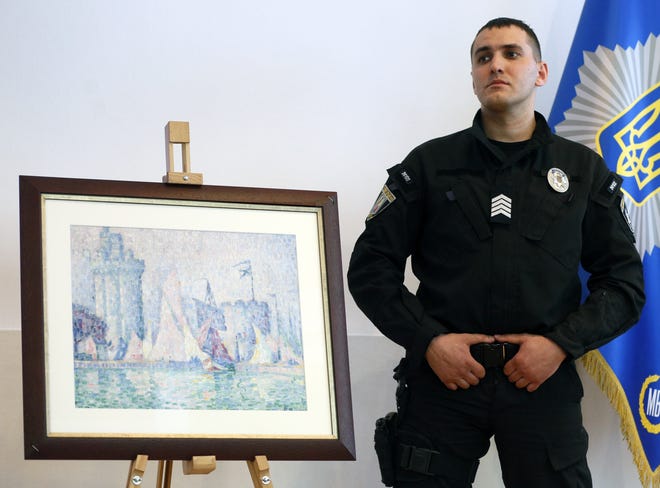 A policeman guards the 1915 painting "Port of La Rochelle" by Paul Signac, stolen from the Museum of Fine Arts in Nancy, France last year, at a briefing in Ukraine 's Interior Ministry in Kiev, Ukraine, Tuesday, April 23, 2019. [AP Photo/Efrem Lukatsky]