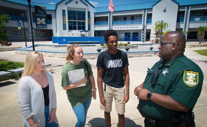 St. Johns County Sheriff's Office Deputy Anthony Harrell, the school's full-time resource officer, talks to Pedro Menendez High School students outside the school in 2018. St. Johns County's public schools use a hybrid system that utilizes 28 armed security guards from an outside company and 25 armed deputies from the St. Johns County Sheriff's Office. [PETER WILLOTT/THE RECORD]