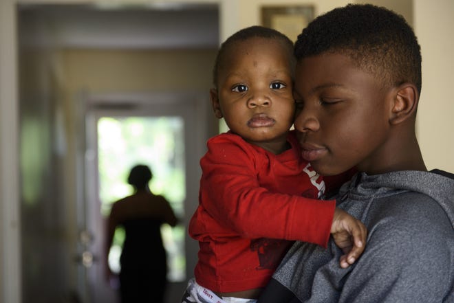Delaun Parker-Elliott Jr., 10, holds his brother Avion Parker-Elliott, 1, at their home Wednesday. The boys' father was shot and killed last week. [Melissa Sue Gerrits/The Fayetteville Observer]