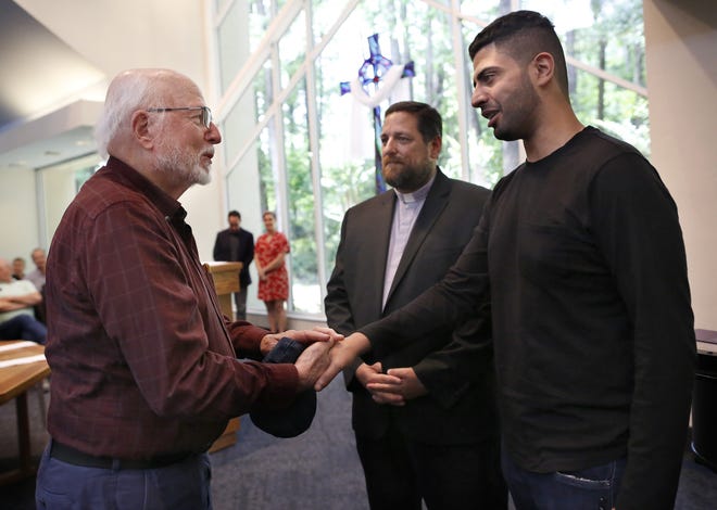 Saoud Al-Ammari, right, is welcomed to Westminster Presbyterian Church by member Sam Trickey, left, and the Rev. Larry Green, on Wednesday in Gainesville. Al-Ammar, who fears persecution in his home country of Qatar, has been given sanctuary by the church’s congregation. [Brad McClenny/The Gainesville Sun]