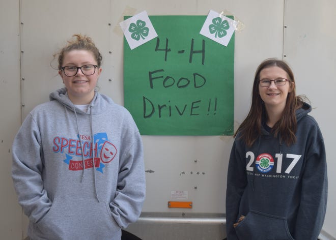 4-H members Krystina Slack, left and Sarah Starasta, right stand near the food collection trailer in past years of a Day of Service. [Photo courtesy of Patty Huffer]