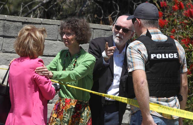 A woman, who appeared to have come out of the the Altman Family Chabad Community Center with the man behind her, where a man with a gun shot multiple people inside, killing one, talks to Minoo Anvari, far left, a member of the Chabad synagogue, on Saturday in Poway, Calif. The man, who appears to have an injury on his right hand, talks to a police officer. (Hayne Palmour IV / San Diego Union-Tribune / TNS)